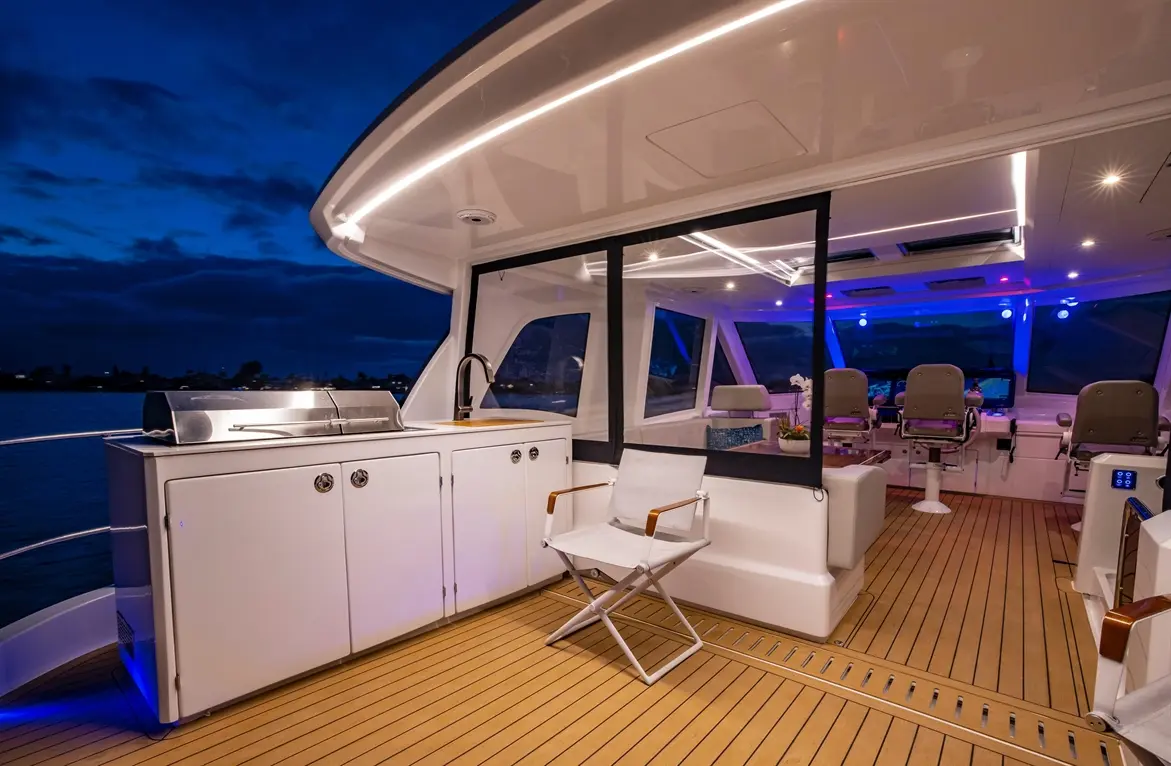 Luxurious yacht interior at night, featuring a modern kitchen, seating area, and vibrant ambient lighting.